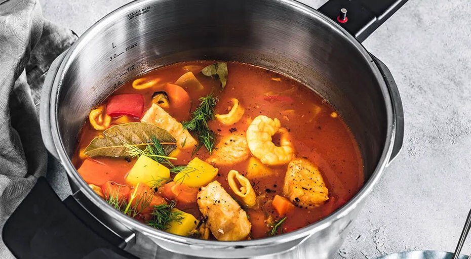Ein Schnellkochtopf von Fissler mit Meeresfrüchtesuppe, gefüllt mit Garnelen, Fisch, Paprika, Karotten und Gewürzen.