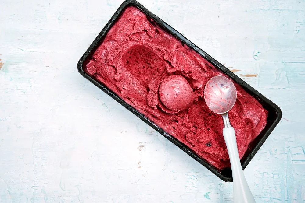 Top view of red berries sorbet with scoop.