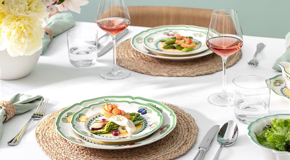 Gedeckter Tisch mit dekorativen Tellern der Serie French Garden von Villeroy &amp; Boch, Gläsern mit Roséwein und Blumendekoration.