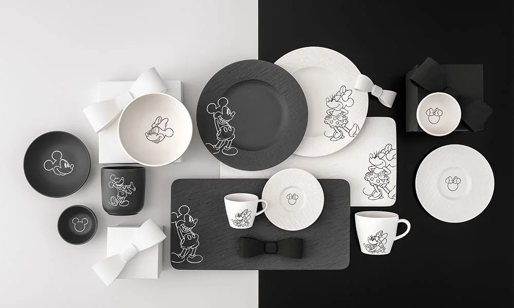 Geschirrset Villeroy &amp; Boch Manufacture Rock – Mickey Mouse in Schwarz-Weiß mit Mickey Mouse-Motiven, bestehend aus Tellern, Tassen und Schalen auf geteiltem Hintergrund.