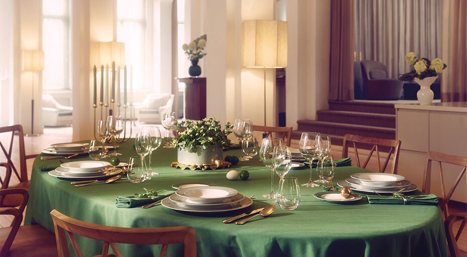 Eleganter Esstisch mit grüner Tischdecke, gedeckt mit Geschirr der Serie Francis Carreau von Rosenthal, Gläsern und goldfarbenem Besteck in einem hellen Raum.