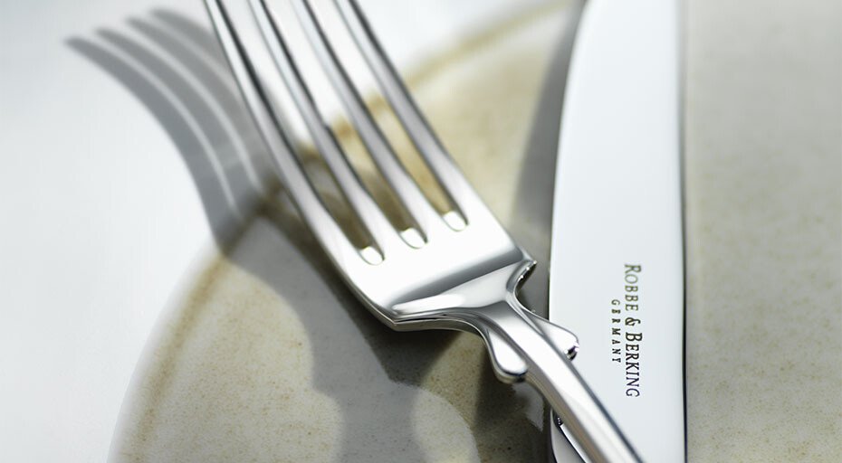 Silberne Gabel und Messer der Serie Alt Spaten von Robbe &amp; Berking auf einem Teller detailreich und elegant inszeniert.