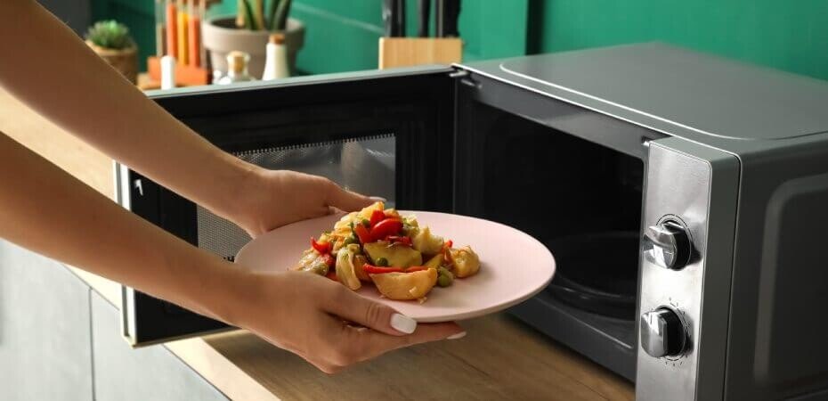 Frau stellt Teller in Mikrowelle