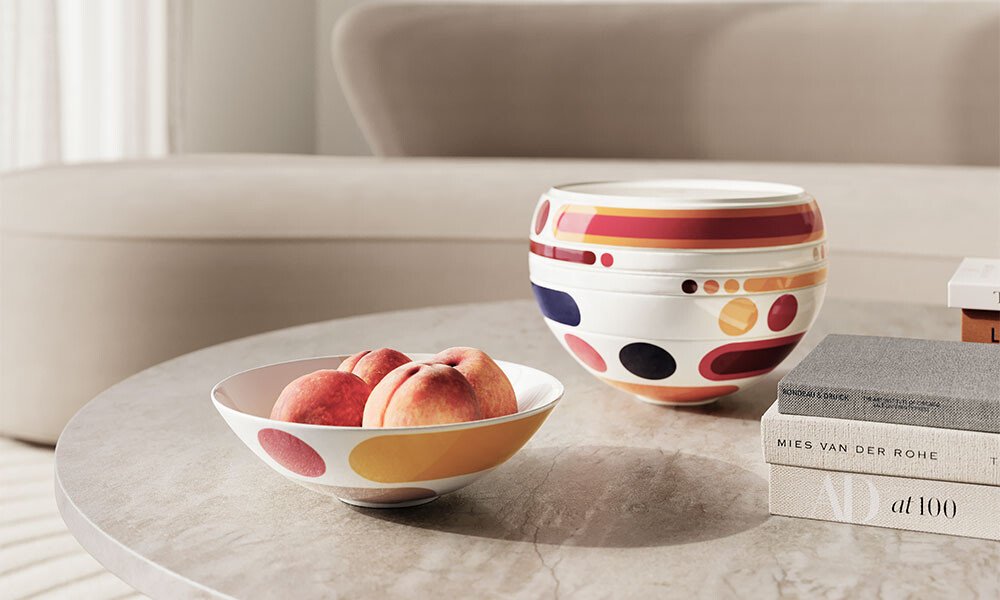 Geschirr-Set La Boule von Villeroy &amp; Boch mit abstrakten Mustern auf Marmortisch, eine Schale mit Pfirsichen gefüllt, dezentes modernes Interieur im Hintergrund.