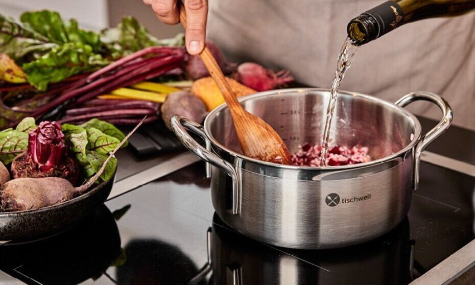 Eine Person nutzt  Aluminium-Kochgeschirr auf einem Herd