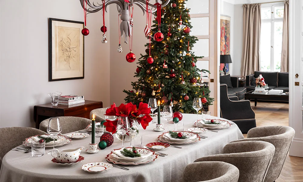 Villeroy &amp; Boch Toy's Delight Porzellan auf festlich gedecktem Esstisch mit Weihnachtsschmuck, Kerzen und Baum im Hintergrund, in modernem Esszimmer arrangiert.