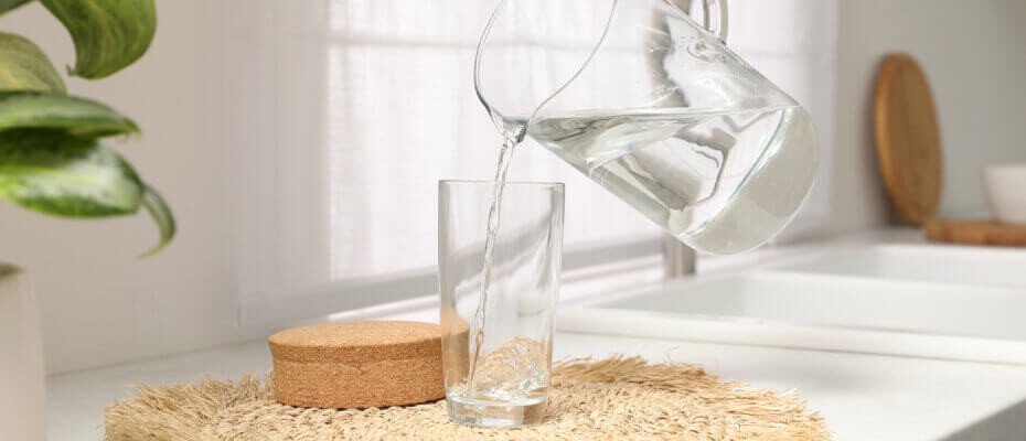 Person kippt Wasser aus einer Glaskanne