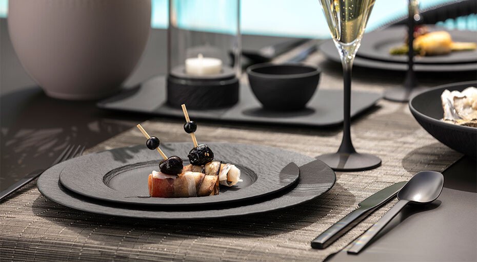 Elegante Tischgedeck mit Gourmet-Vorspeise, modernen Besteck der Serie Manufacture von Villeroy &amp; Boch und Sektglas, auf stilvoll dekoriertem Tisch.