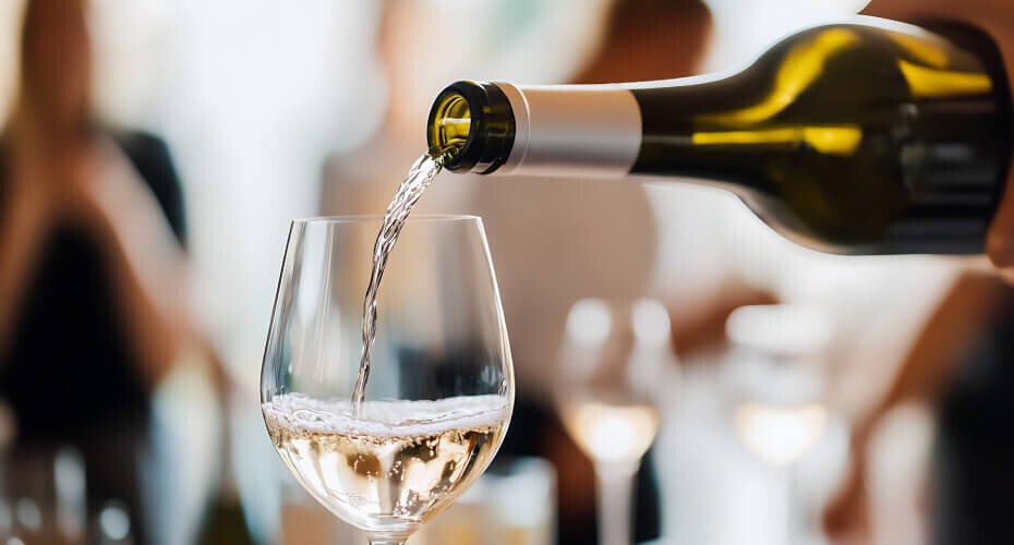 Eine Person gießt Riesling in ein Rieslingglas ein.