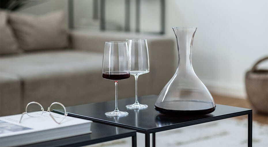 Wein-Dekanter und zwei Weingläser von Zwiesel Glas mit Rotwein auf modernen, schwarzen Tischen im Wohnzimmer.