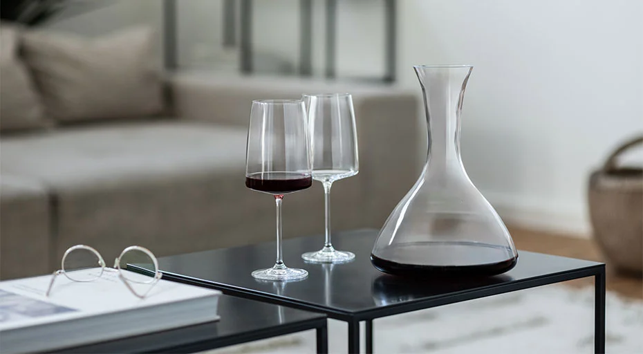 Wein-Dekanter und zwei Weingläser von Zwiesel Glas mit Rotwein auf modernen, schwarzen Tischen im Wohnzimmer.