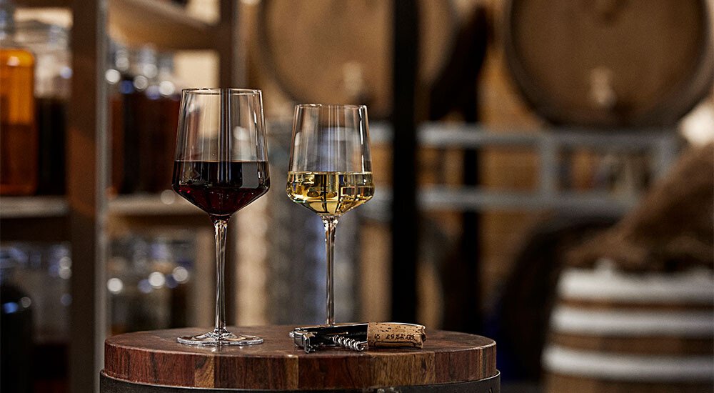 Ein Weingläser-Set auf einem Holzfass