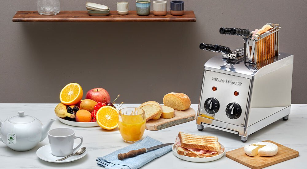 Ein Sandwichtoaser auf einem Tisch mit Geschirr und Produkten für ein leckeres Frühstück