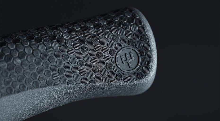 Nahaufnahme eines ergonomischen Griffs mit hexagonalem Muster und Markierungslogo, vor schwarzem Hintergrund.