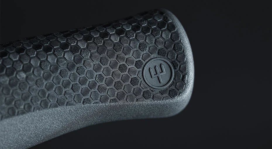 Nahaufnahme eines ergonomischen Griffs mit hexagonalem Muster und Markierungslogo, vor schwarzem Hintergrund.