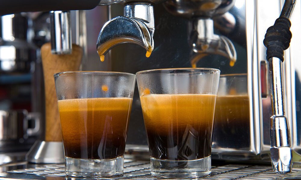 Espressomaschine brüht zwei Gläser Espresso mit dichter Crema.