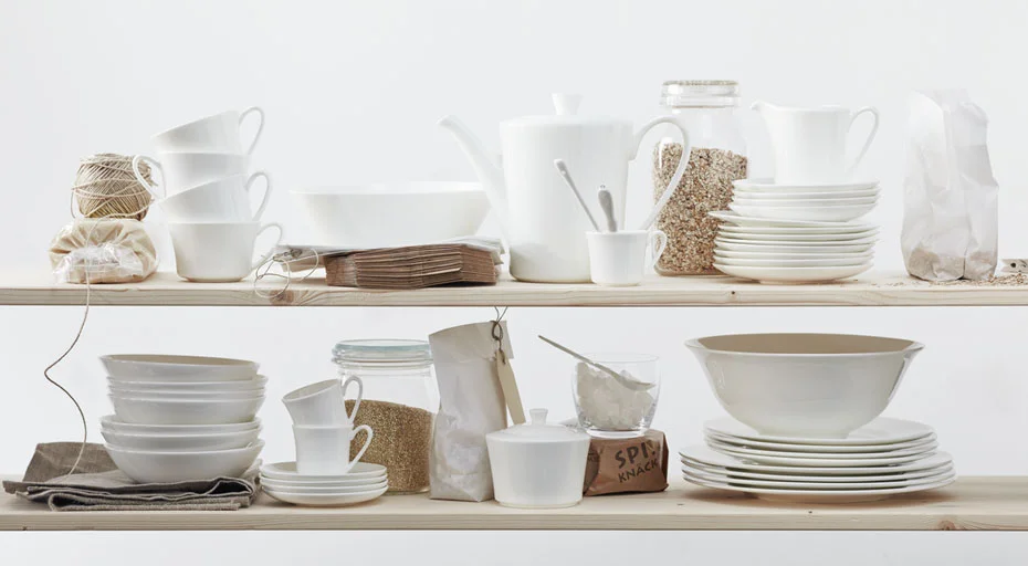 Weißes Geschirr der Serie Jade weiß von Rosenthal und diverse Küchenutensilien auf Regalen arrangiert, umgeben von Naturmaterialien wie Juteschnur und Stoff.