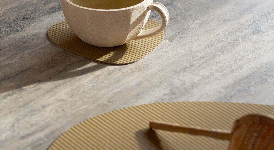 Tasse auf Untersetzer der Serie Corduroy von Lind DNA auf grauer Steinoberfläche, im Sonnenlicht.