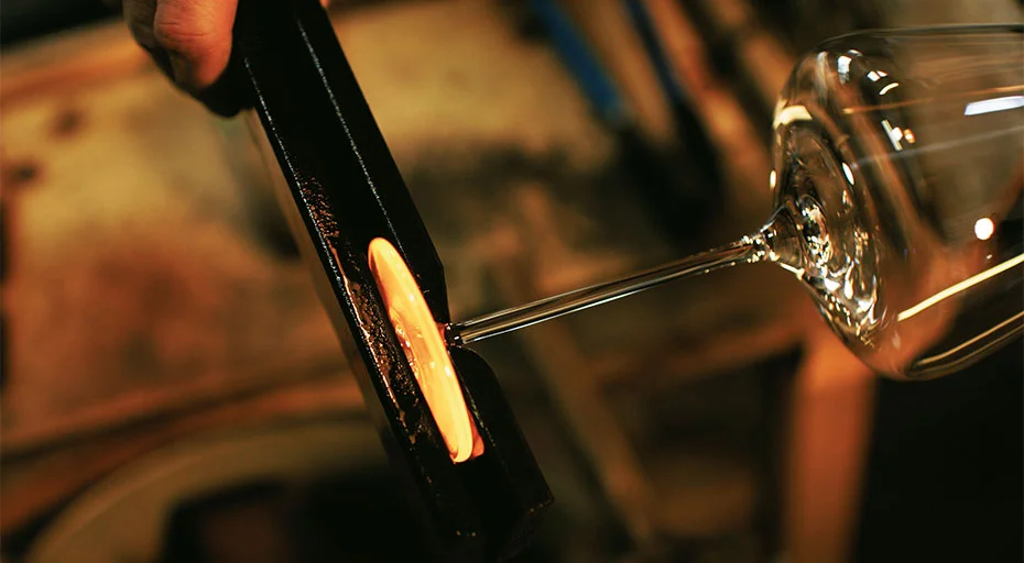Glasbläser formt erhitztes Glas von Zalto mit Zange zu einem Glasstiel in traditionellem Herstellungsprozess.