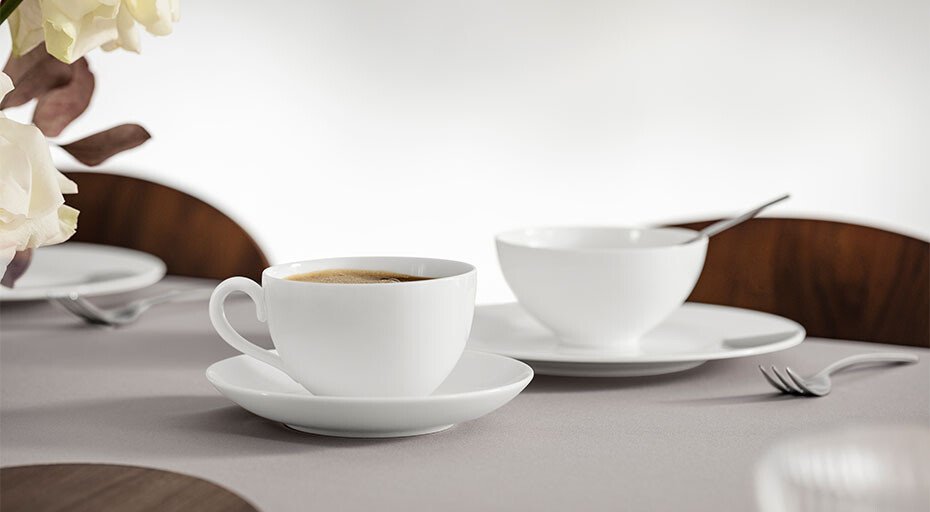 Kaffeetasse aus Fine Bone China und Schale auf gedecktem Tisch mit minimalistischer Dekoration.