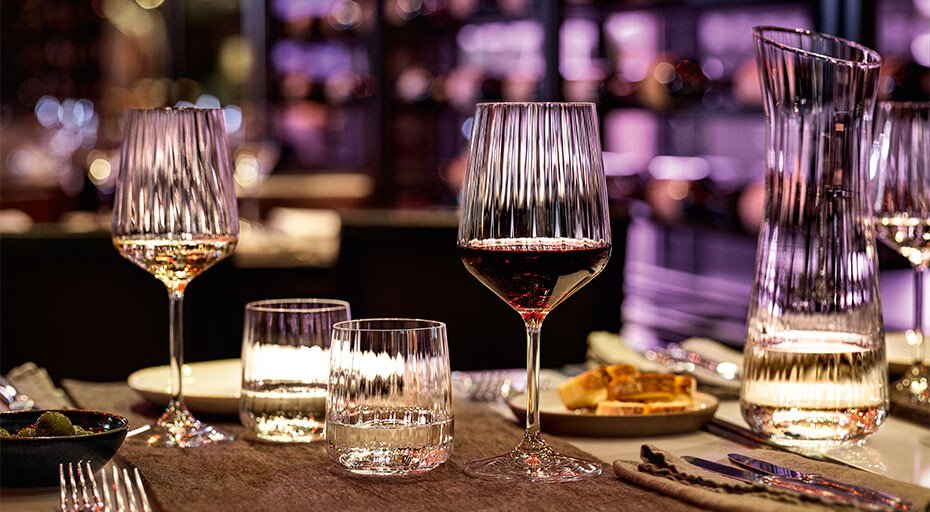 Eleganter Abendtisch mit Weingläsern, Karaffe, Wassergläsern der Serie Lifestyle von Spiegelau und Snacks in stimmungsvoller, gedimmter Beleuchtung.