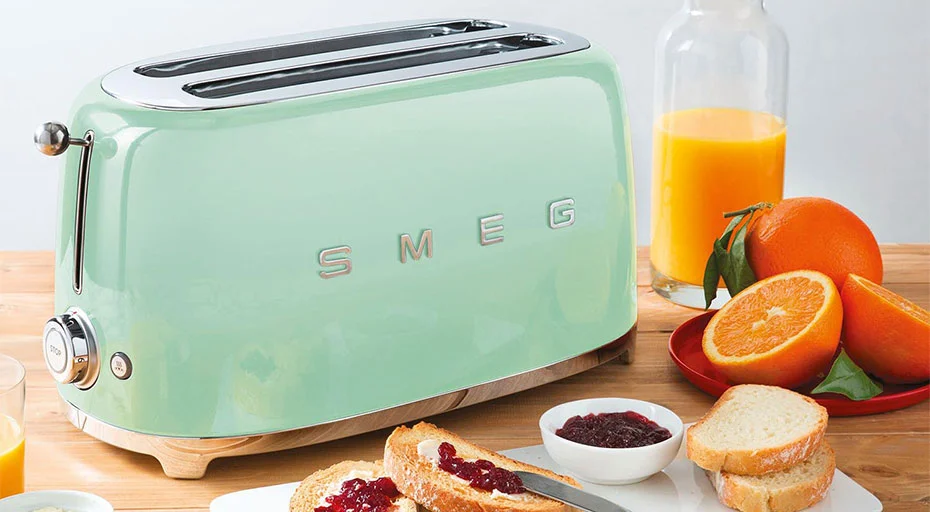 Retro Toaster von SMEG auf Tisch mit Saft, Orangen und Toast mit Marmelade, stilvolle Küchenszene.