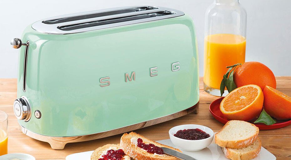 Retro Toaster von SMEG auf Tisch mit Saft, Orangen und Toast mit Marmelade, stilvolle Küchenszene.