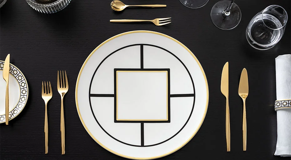 Elegantes Tischgedeck mit geometrischem Villeroy &amp; Boch MetroChic Porzellanteller, goldfarbenem Besteck und kristallklaren Trinkgläsern.