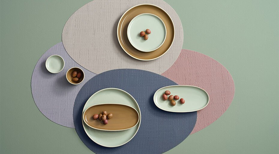 Minimalistische Tischdekoration mit geometrischen Servietten, pastellfarbenem Geschirr der Serie Semana von ASA und kleinen Steinen.