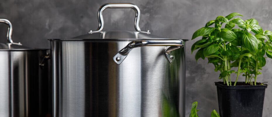 Ein Edelstahl-Topf steht neben einem Basilikum