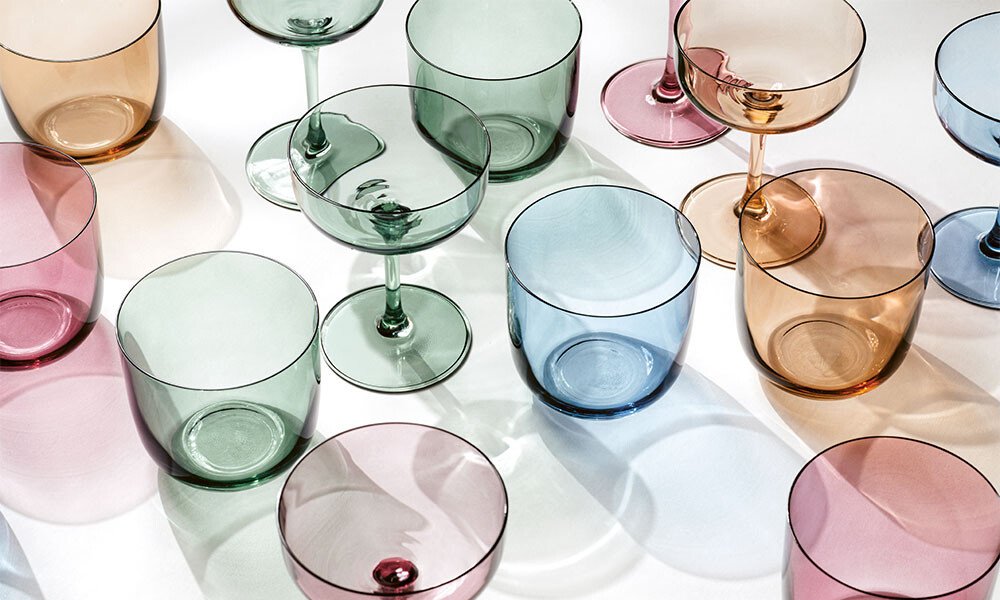 Verschiedenfarbige, transparente Gläser der Like-Serie von Villeroy &amp; Boch in unterschiedlichen Formen auf weißem Hintergrund, aus verschiedenen Blickwinkeln fotografiert.