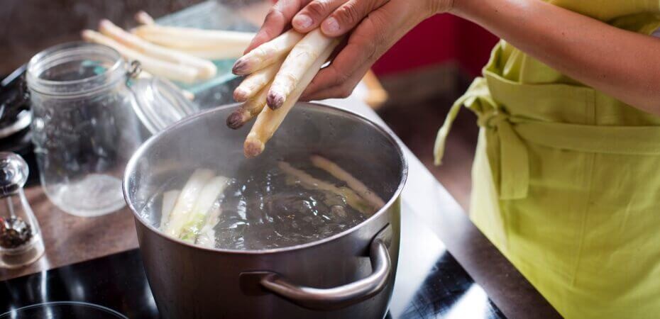 Frau macht Spargel in einen Topf