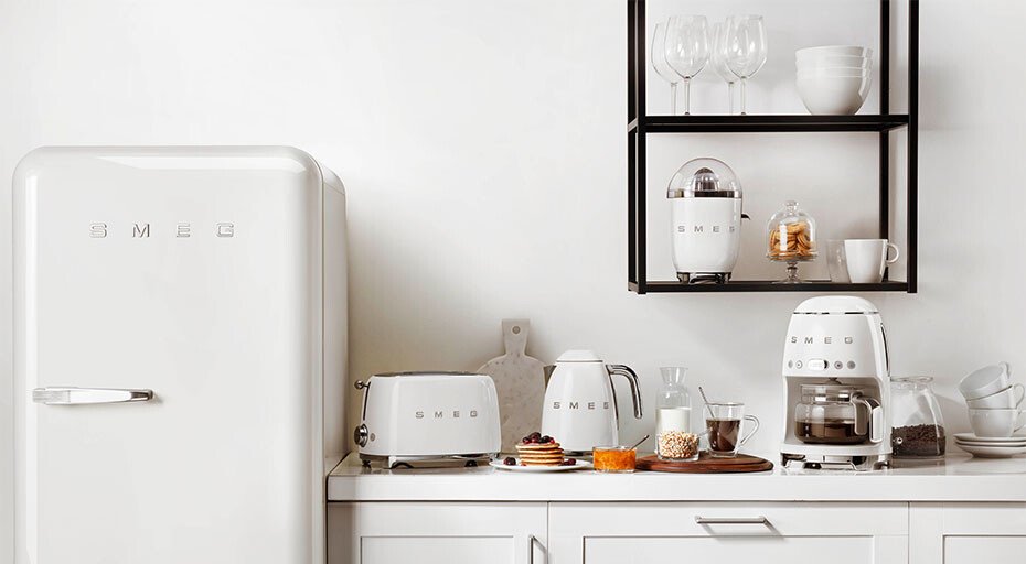 Moderne Küche mit weißen SMEG-Kleingeräten: Kühlschrank, Toaster, Wasserkocher, Kaffeemaschine und Küchenregal.
