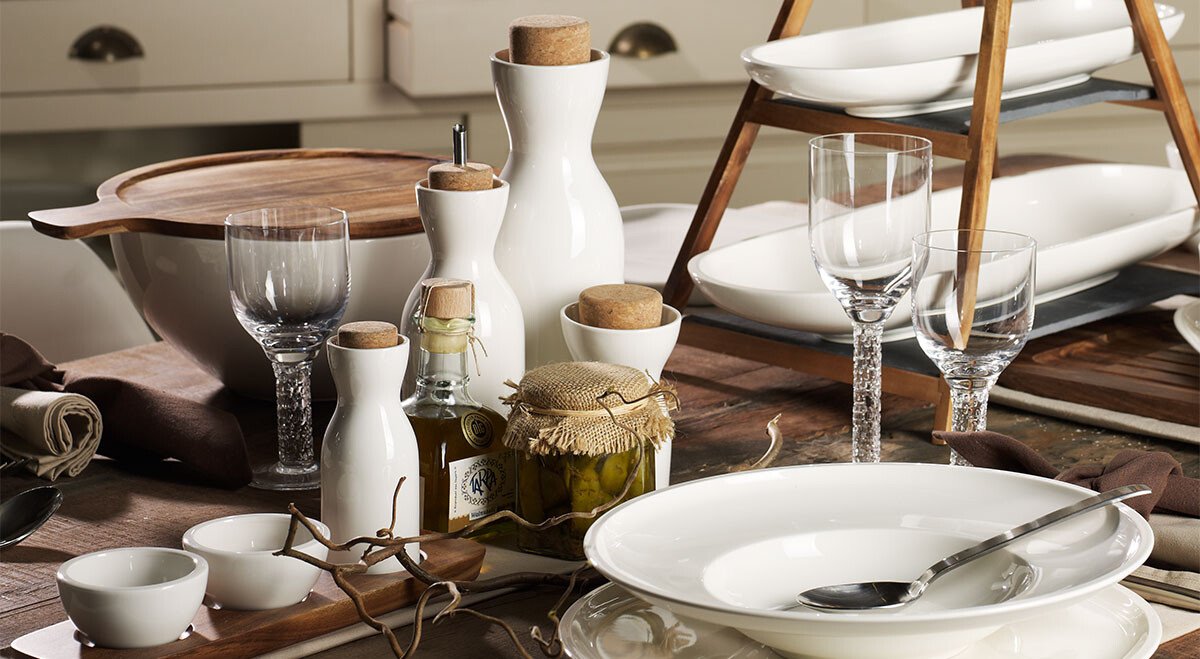 Tisch mit Geschirr der Serie Artesano von Villeroy &amp; Boch, Besteck, Gläsern, Gewürzen und einer Etagere, arrangiert für ein elegantes Essen in rustikaler Umgebung.