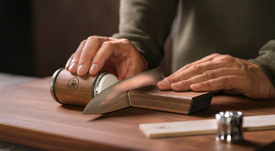 Person schleift ein Messer mit einem HORL®-Rollschleifer auf einem Tisch. Daneben die Lupe von HORL®.