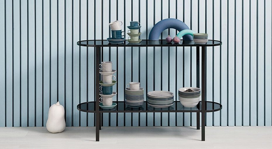 Regal mit gestapeltem Geschirr der Serie Trend von Thomas und Deko auf blau-weiß gestreiftem Hintergrund.